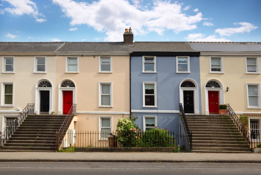 small three-story house stands beside road. doors, windows, stairs